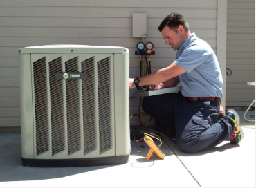 Photo of a technician completing a routine maintenance check up on a residential exterior AC unit.  